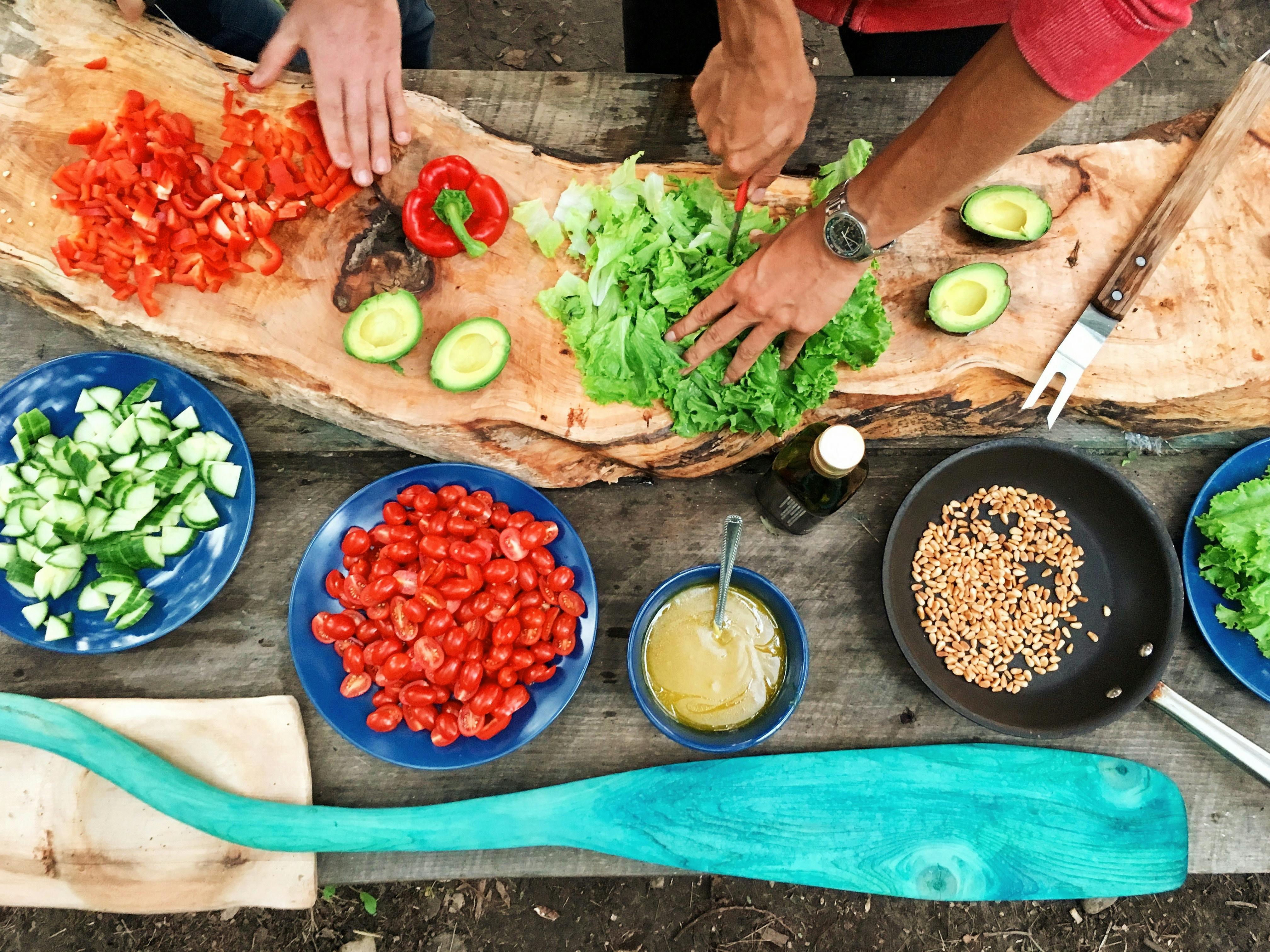 Fresh vegetables and herbs on a wooden cutting board with cooking utensils